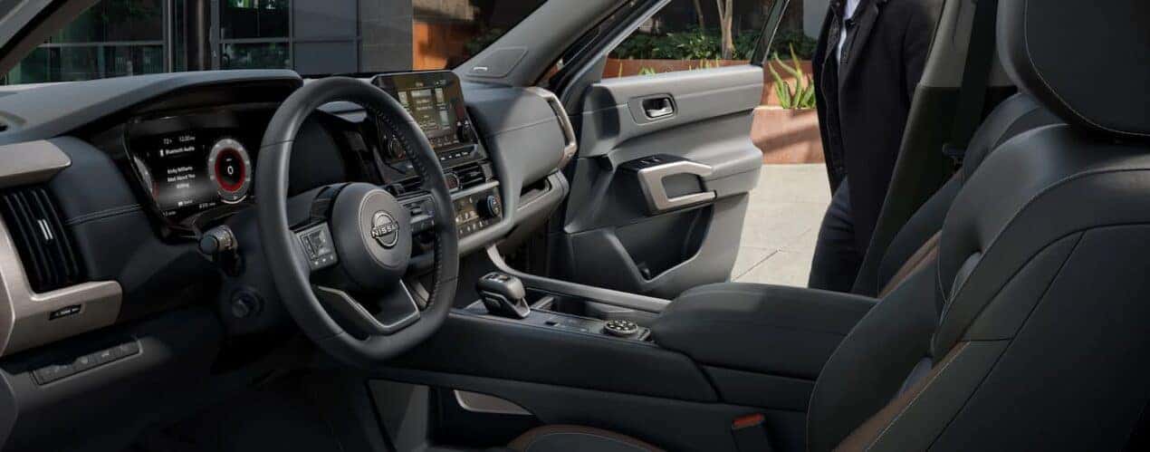 A man is shown opening the passenger door of a 2023 Nissan Pathfinder Platinum.