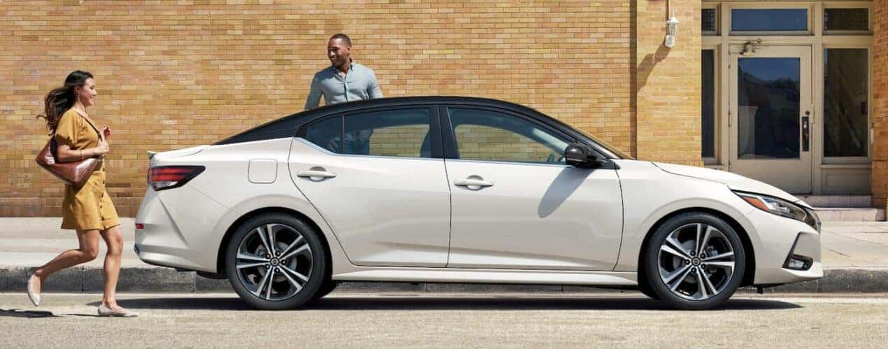 A white 2023 Nissan Sentra is shown from the side parked on a city street.
