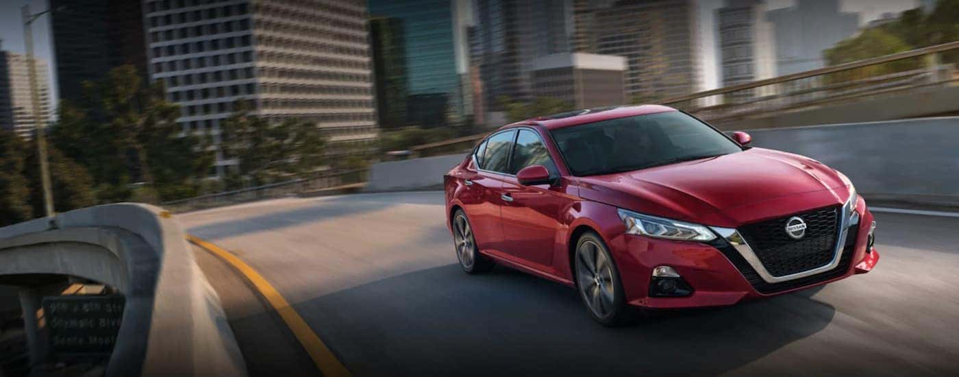 Red 2021 Nissan Altima is shown driving on highway overpass
