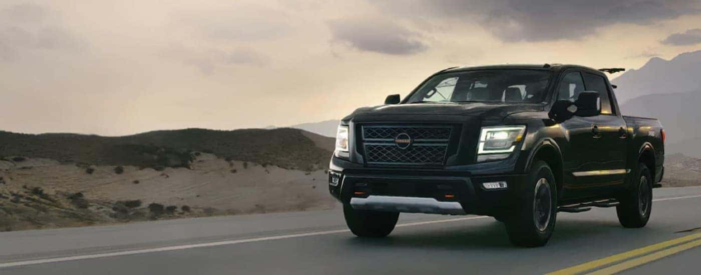 A black 2021 Nissan Titan is shown from a front angle driving on an open road.