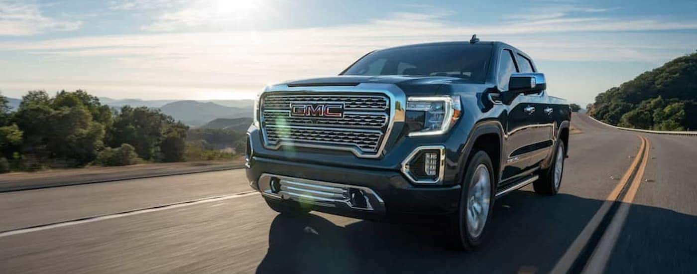 A grey 2020 GMC Sierra 1500 Denali is shown driving on an open road after leaving a used truck dealer.