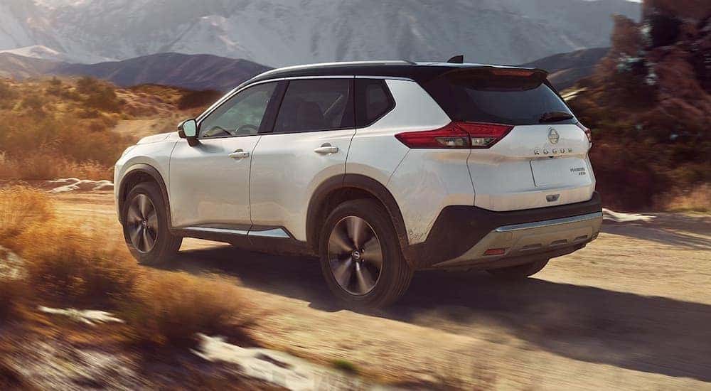 A white 2023 Nissan Pathfinder is shown from the rear at an angle after leaving a dealer that has a Nissan Rogue for sale near Mahomet, IL.