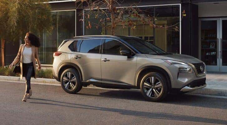 A grey 2023 Nissan Rogue is shown from the side parked on a city street.