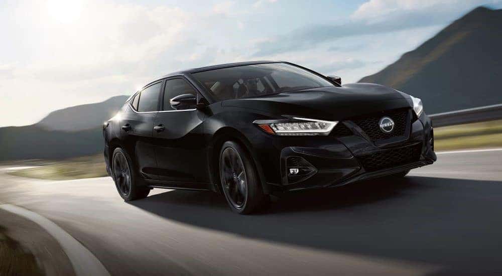 A black 2023 Nissan Maxima SR is shown driving on an open road.