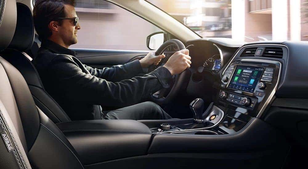 A person is shown driving a 2023 Nissan Maxima for sale.