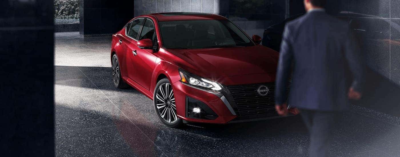 A red 2023 Nissan Altima SL is shown parked at a hotel lobby.