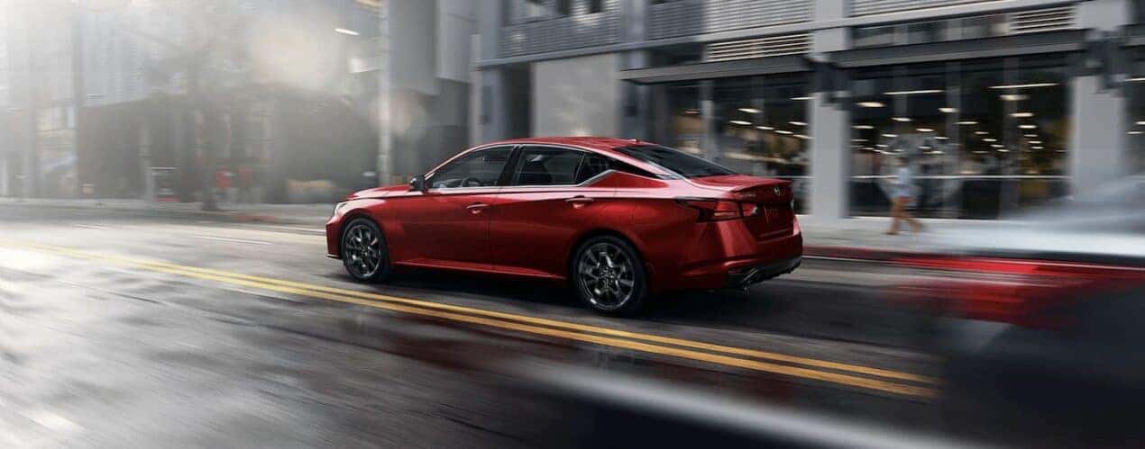 A red 2023 Nissan Altima SR is shown from the side driving on a city street.
