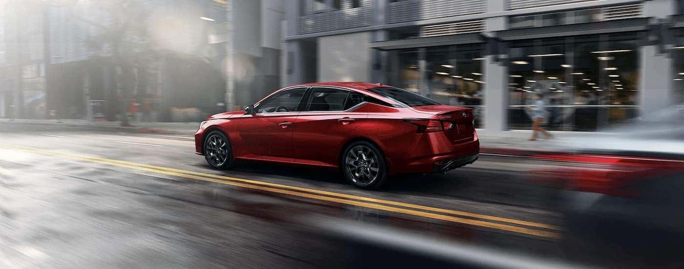 A red 2023 Nissan Altima SR is shown from the side driving on a city street.