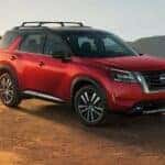 A red and black 2024 Nissan Pathfinder is shown parked on a mountain after viewing Nissan SUVs for sale.