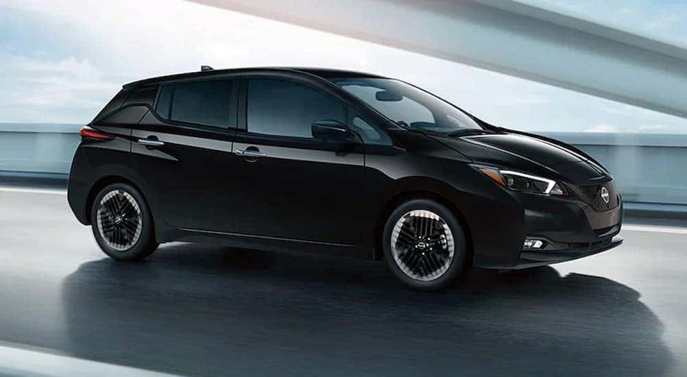 A black 2024 Nissan Leaf SV PLUS is shown driving on a bridge.