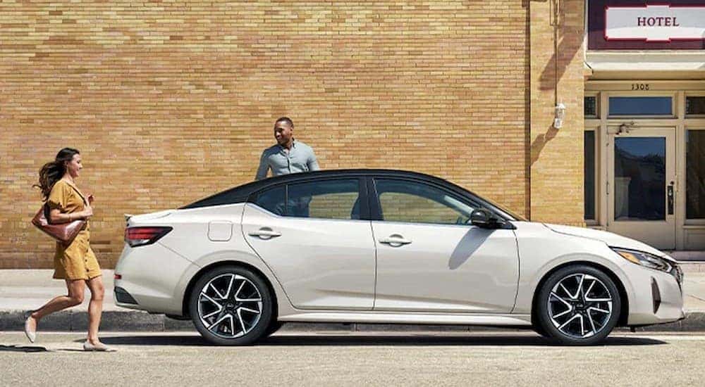 A black and white 2024 Nissan Sentra is shown parked near a hotel.