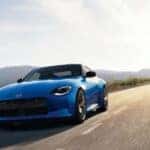 A blue 2024 Nissan Z is shown driving on a road to visit a Decatur Nissan dealer.