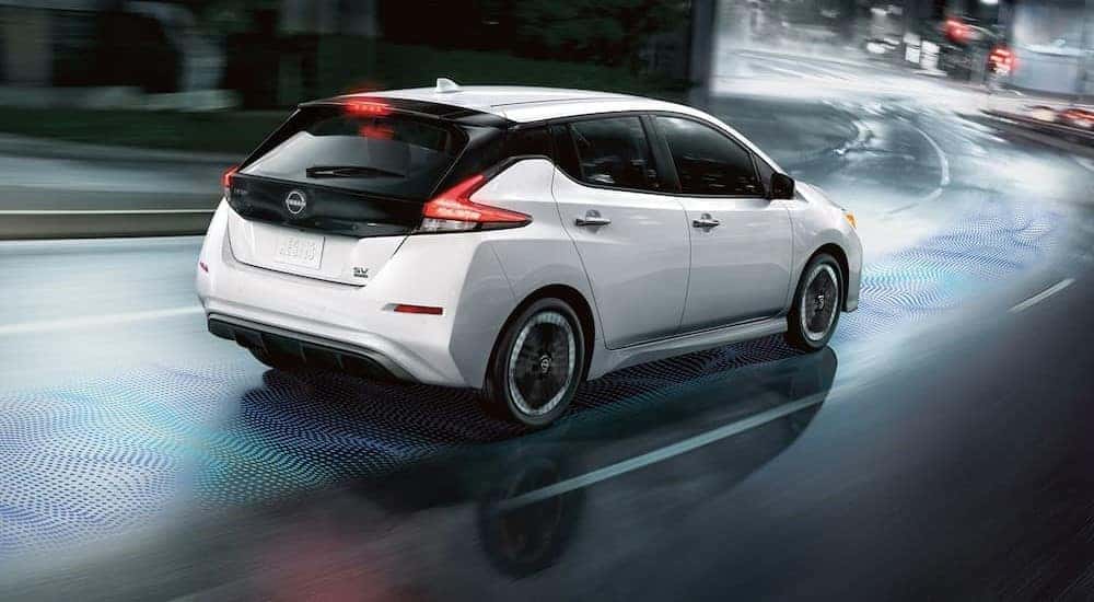 A white 2024 Nissan LEAF SV is shown driving on a city street.