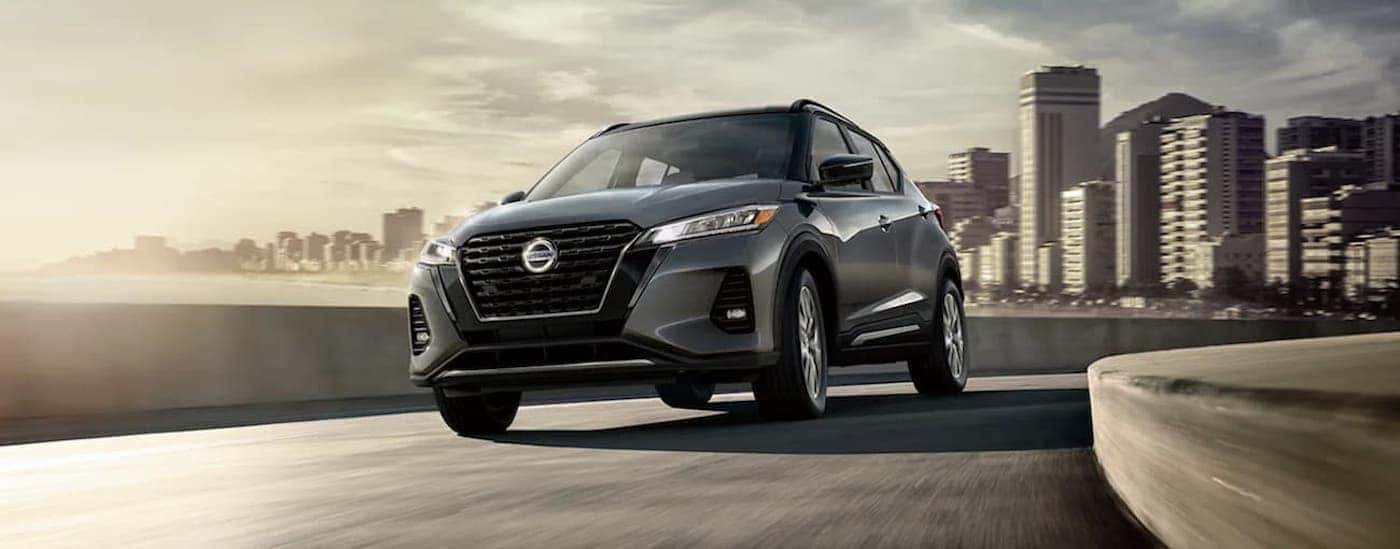 A grey 2021 Nissan Kicks is shown driving from a city.