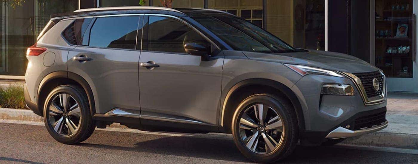 A grey 2021 Nissan Rogue is shown parked by a building.