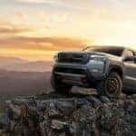 A grey 2024 Nissan Frontier is shown parked on a rocky cliff after visiting a Nissan dealer near Bloomington, IL.