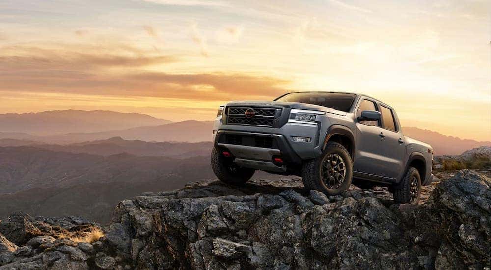 A grey 2024 Nissan Frontier is shown parked on a rocky cliff after visiting a Nissan dealer near Bloomington, IL.