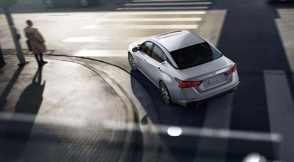 A silver 2024 Nissan Altima is shown from a high angle while driving in a city.