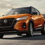 An orange 2024 Nissan Kicks SR with cityscape in the background.