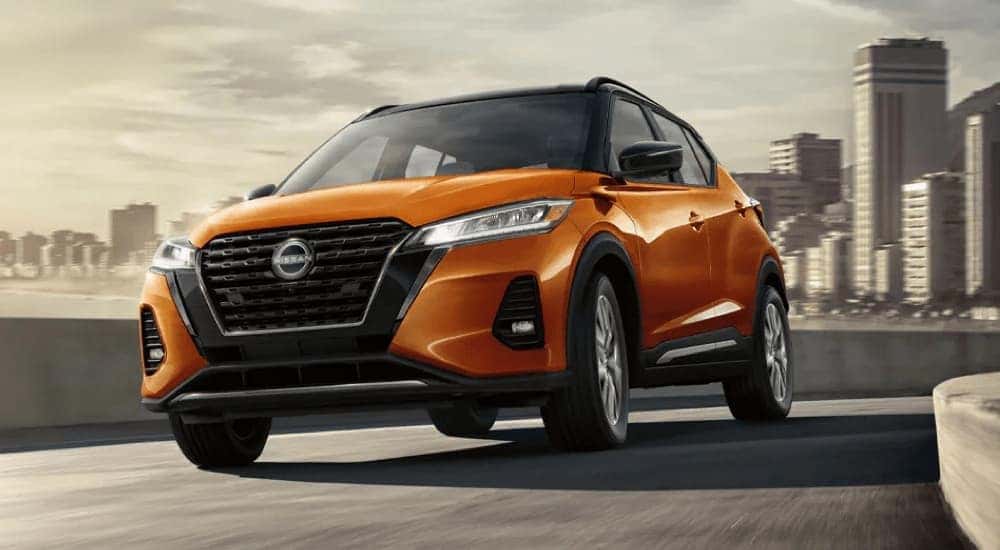 An orange 2024 Nissan Kicks SR with cityscape in the background.