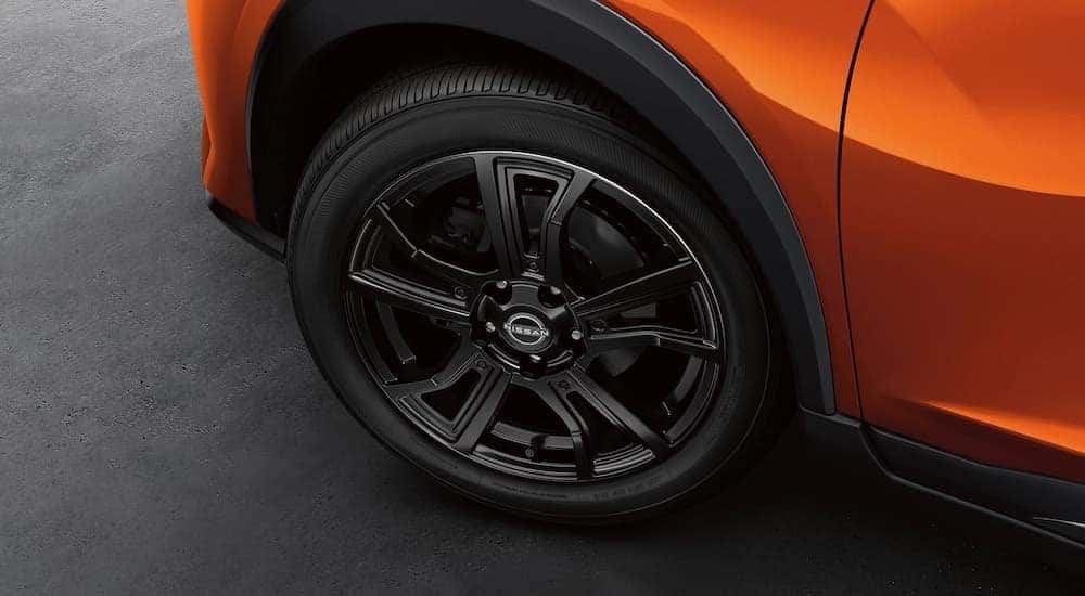 A close-up on the wheel of an orange 2024 Nissan Kicks is shown.