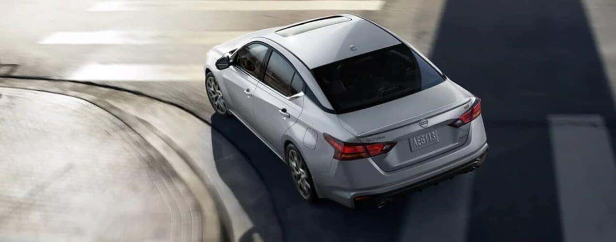 A silver 2024 Nissan Altima SR is driving on a city street.