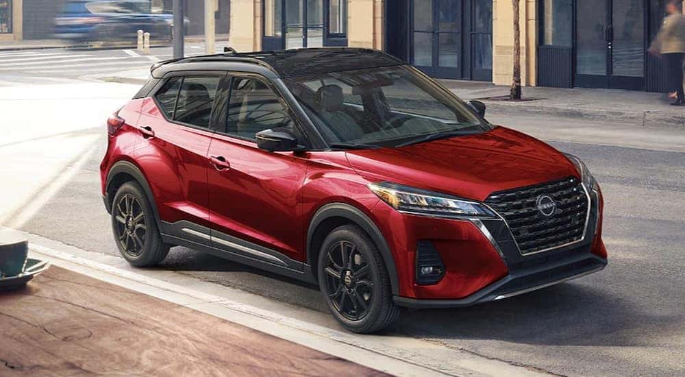 A red 2024 Nissan Kicks is shown parked near a coffee shop.