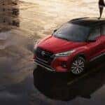 A red 2024 Nissan Kicks for sale near Urbana is shown parked on a puddle.