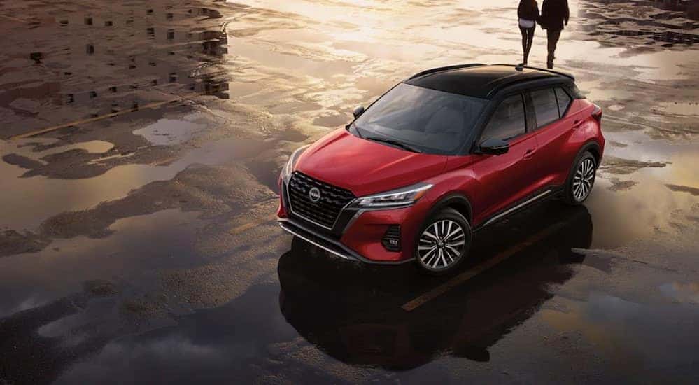 A red 2024 Nissan Kicks for sale near Urbana is shown parked on a puddle.