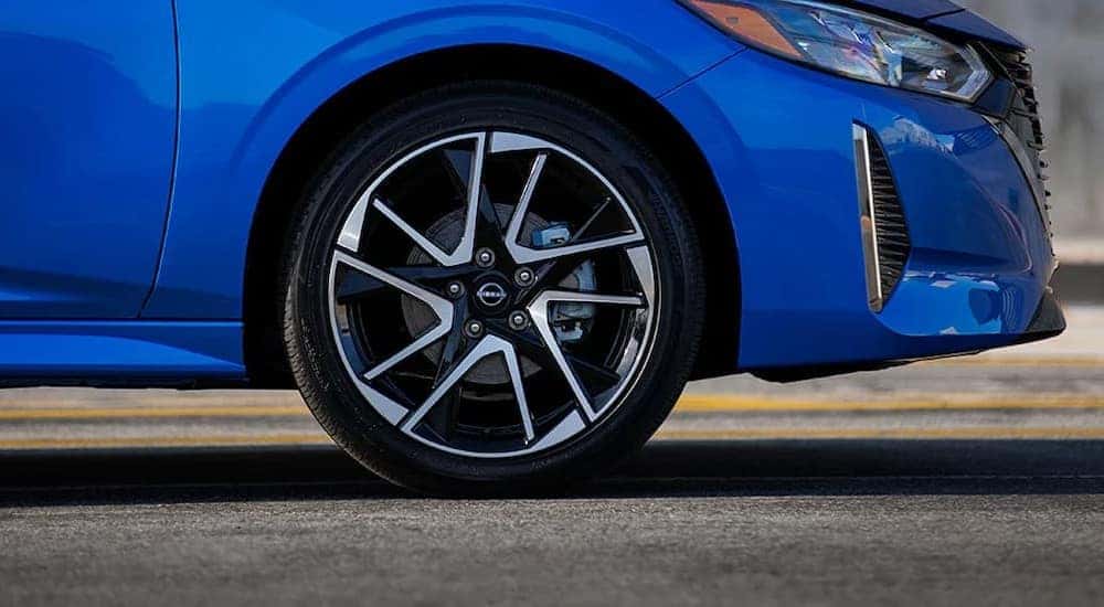 A close-up of the wheel on a blue 2024 Nissan Sentra is shown.