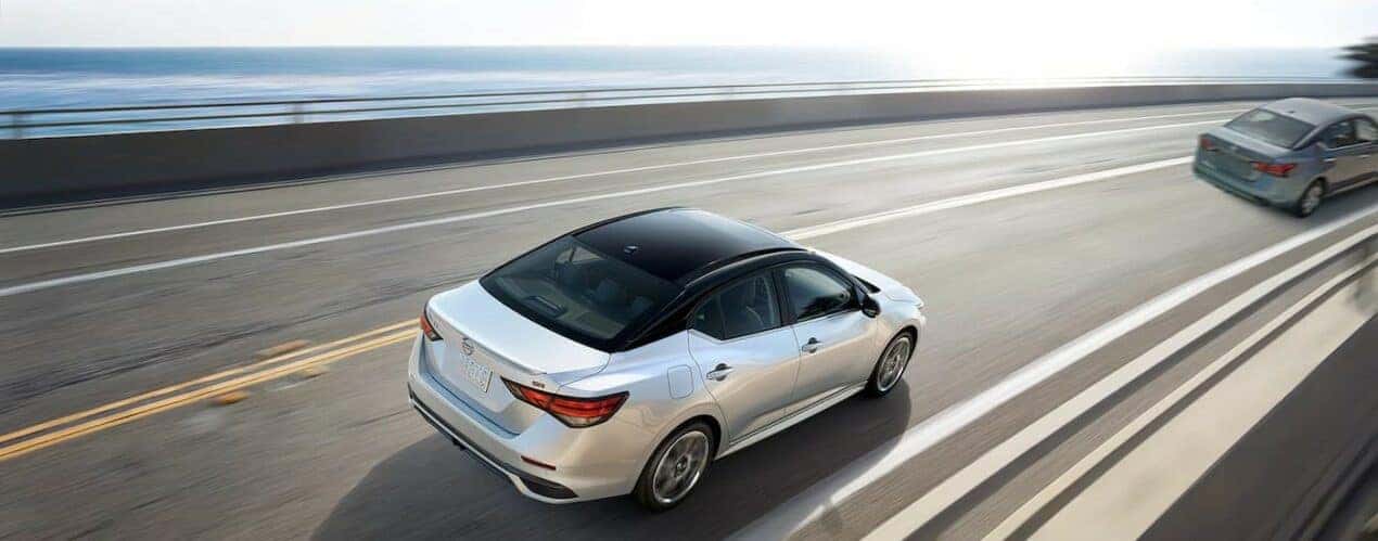 A white 2024 Nissan Sentra SR is shown driving on a highway.