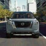 A gray 2024 Nissan Pathfinder is shown driving on a city street.