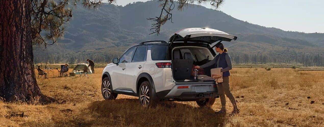 A white 2024 Nissan Pathfinder is parked near a campsite.
