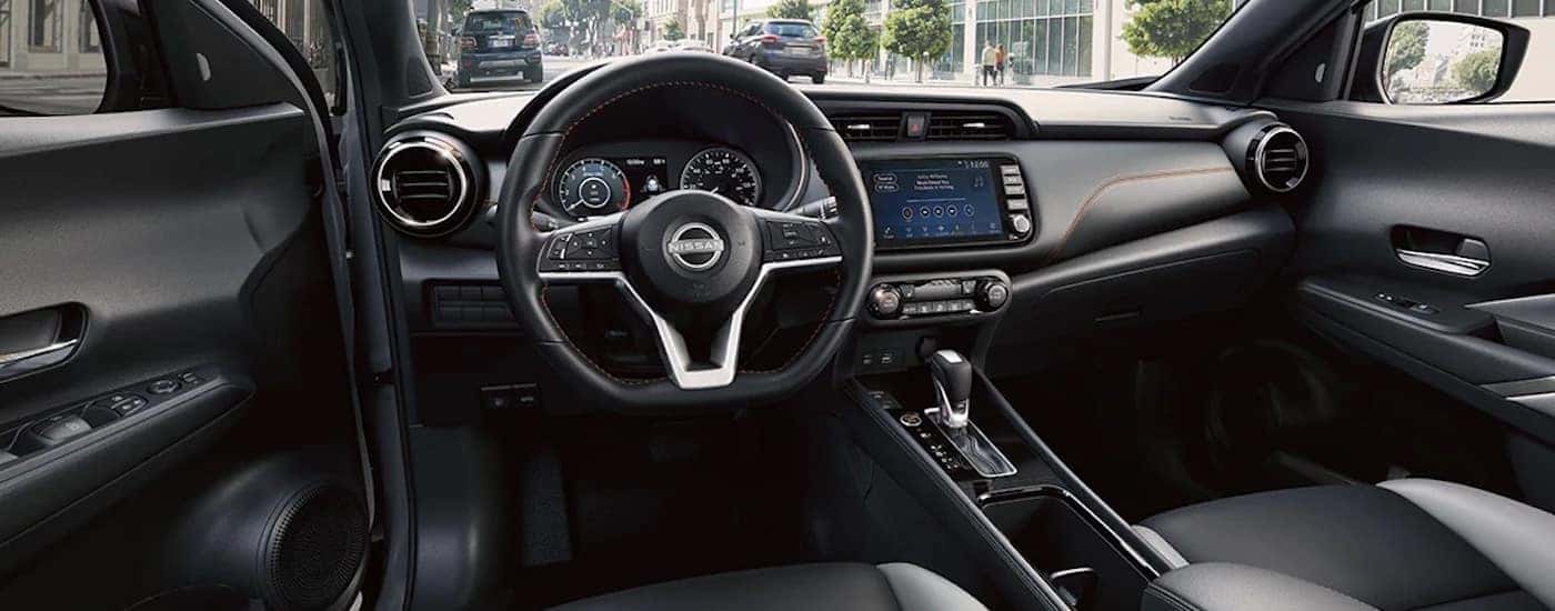 The black interior of a 2024 Nissan Kicks is shown from the driver's seat.