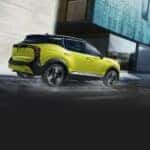 A yellow 2025 Nissan Kicks for sale near Savoy is shown driving.