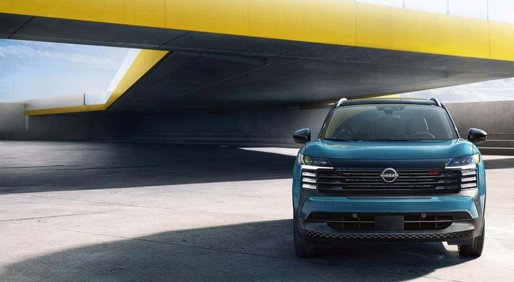 A blue 2025 Nissan Kicks SR parked in front of a yellow wall.