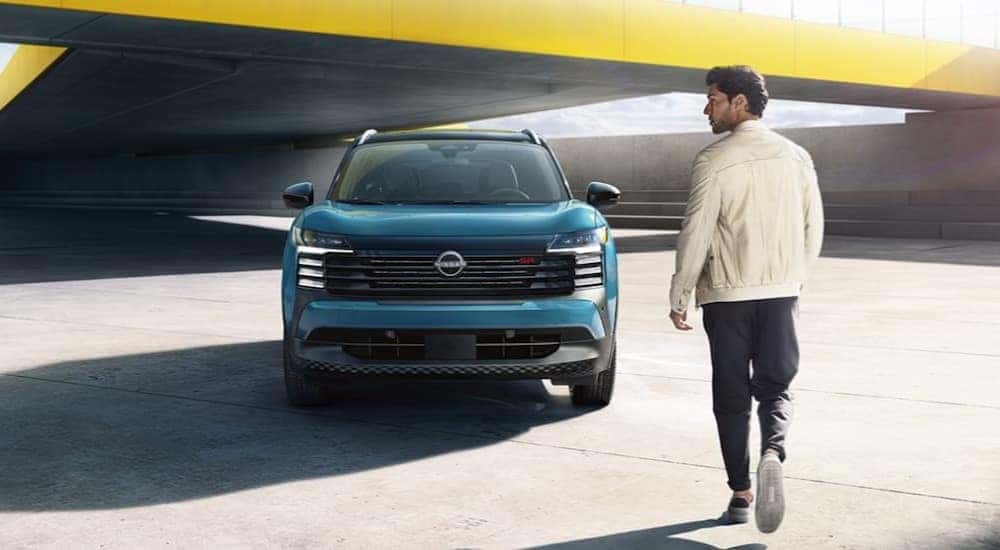 A person is shown walking towards a green 2025 Nissan Kicks SR.