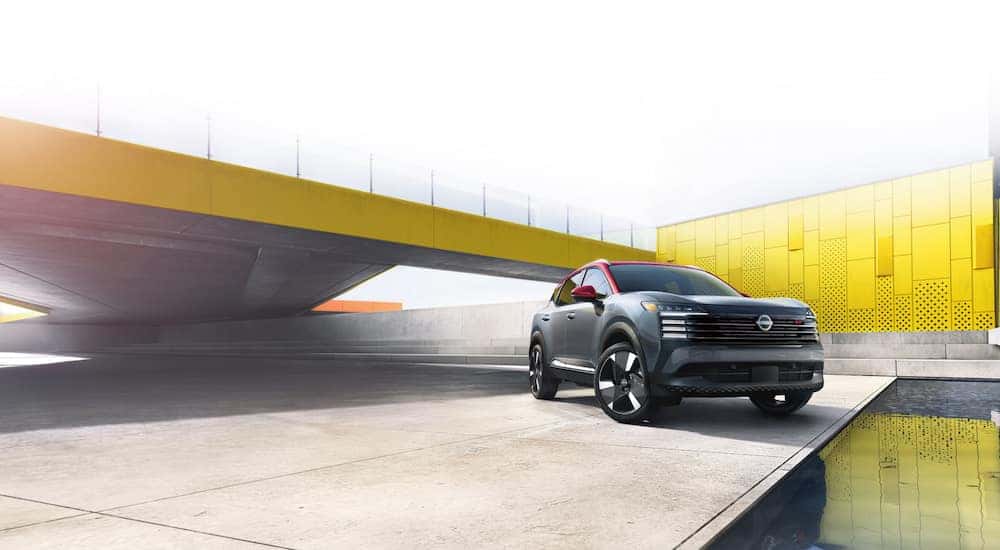 A grey and red 2025 Nissan Kicks SR parked near a water feature.