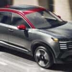 A grey 2025 Nissan Kicks driving on a city street.