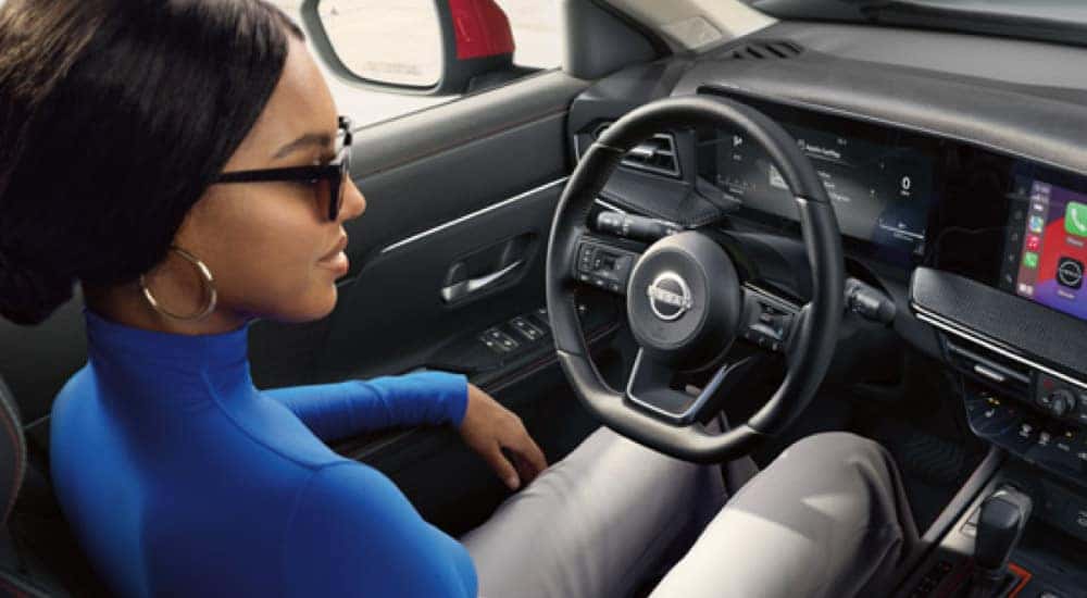 A woman is shown sitting in the driver's seat of a 2025 Nissan Kicks.