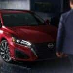A red 2024 Nissan Altima for sale is shown parked near a person.