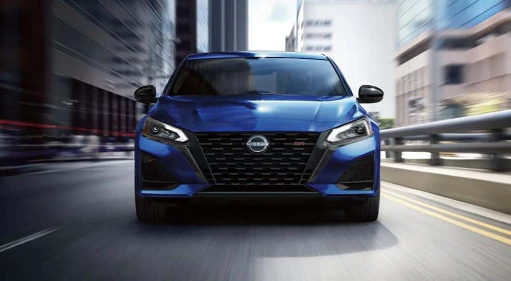A blue 2024 Nissan Altima SR is shown driving on a city street.