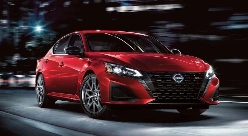 A red 2024 Nissan Altima SR is shown driving on a city street.
