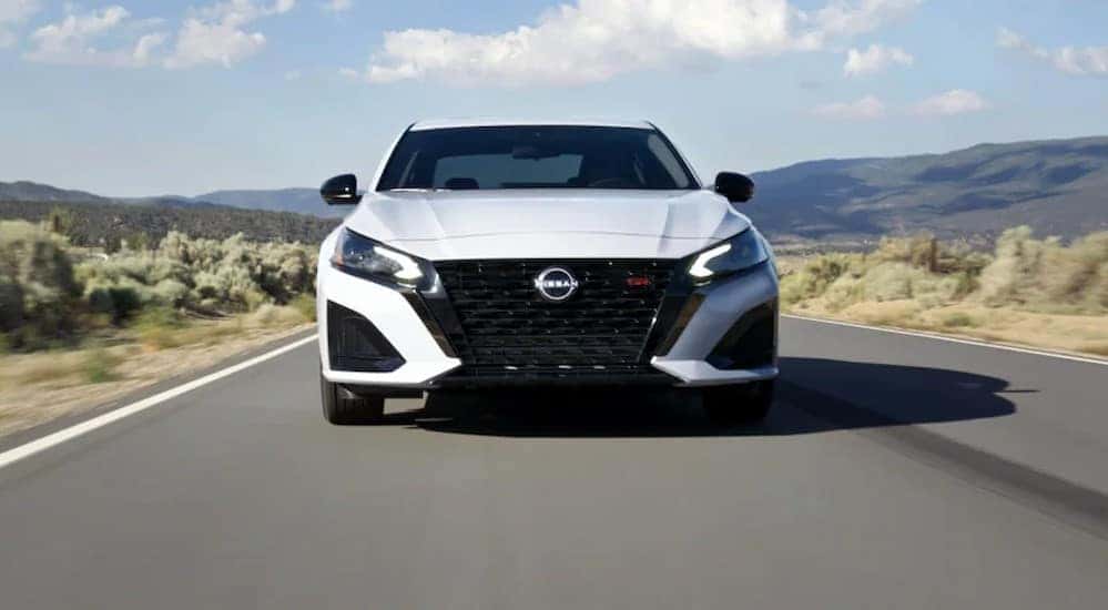 A white 2024 Nissan Altima SR is shown driving on a highway.