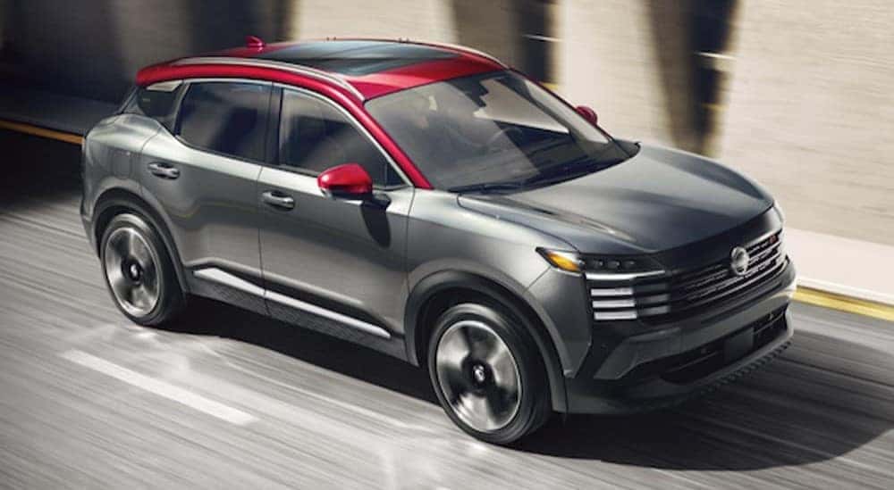 A gray and red 2025 Nissan Kicks SR is shown driving on a city street.