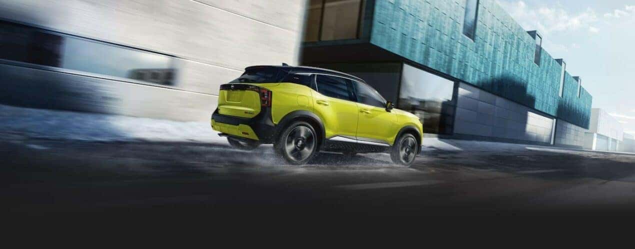 A green 2025 Nissan Kicks is shown driving on a wet road.