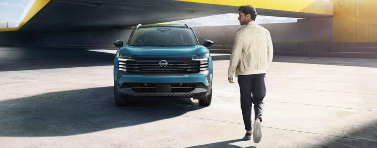 A person is shown walking near a 2025 Nissan Kicks SR.