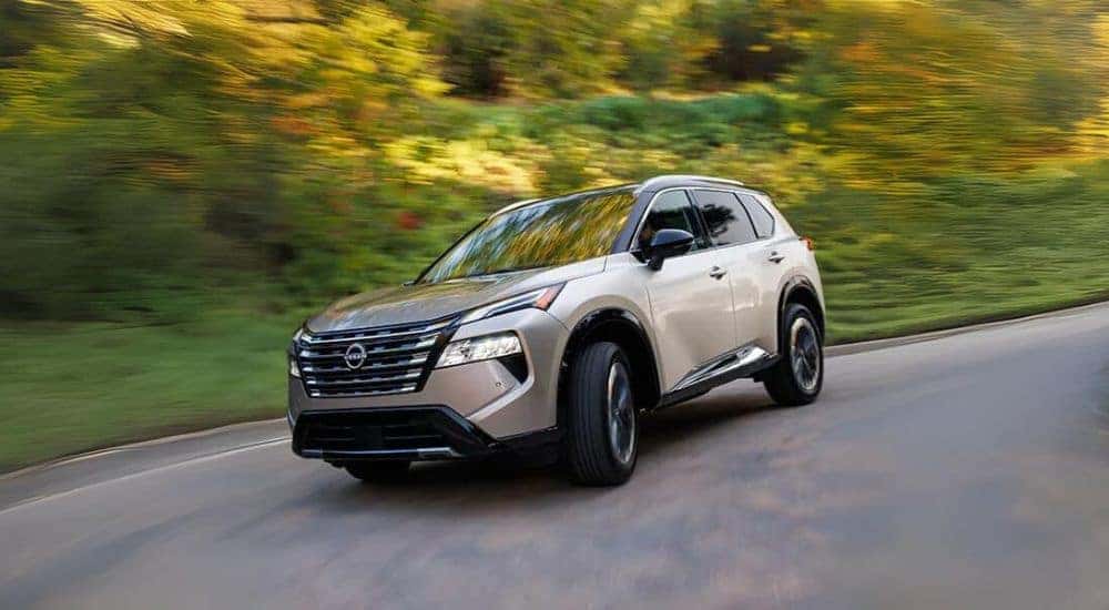 A tan 2024 Nissan Rogue is shown rounding a corner.