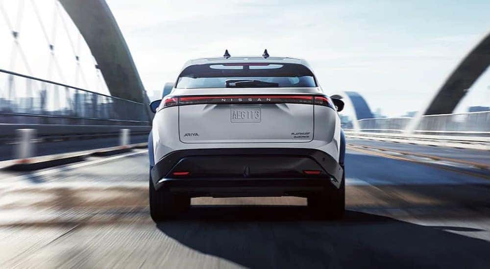 A white 2024 Nissan ARIYA Platinum is shown driving on a bridge.