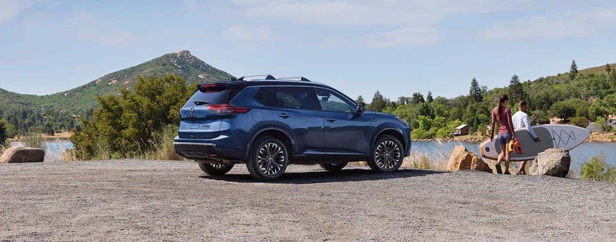 A blue 2024 Nissan Rogue Platinum is parked near a lake.